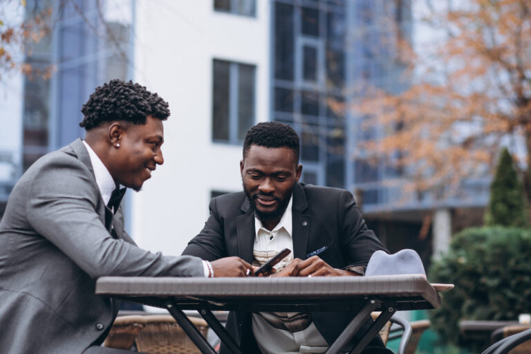 About two african business man sitting outside cafe